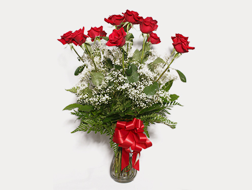 a bouquet of red roses and baby&#39;s breath in a glass vase