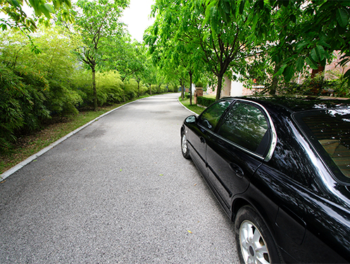 a black car parked on a road with trees