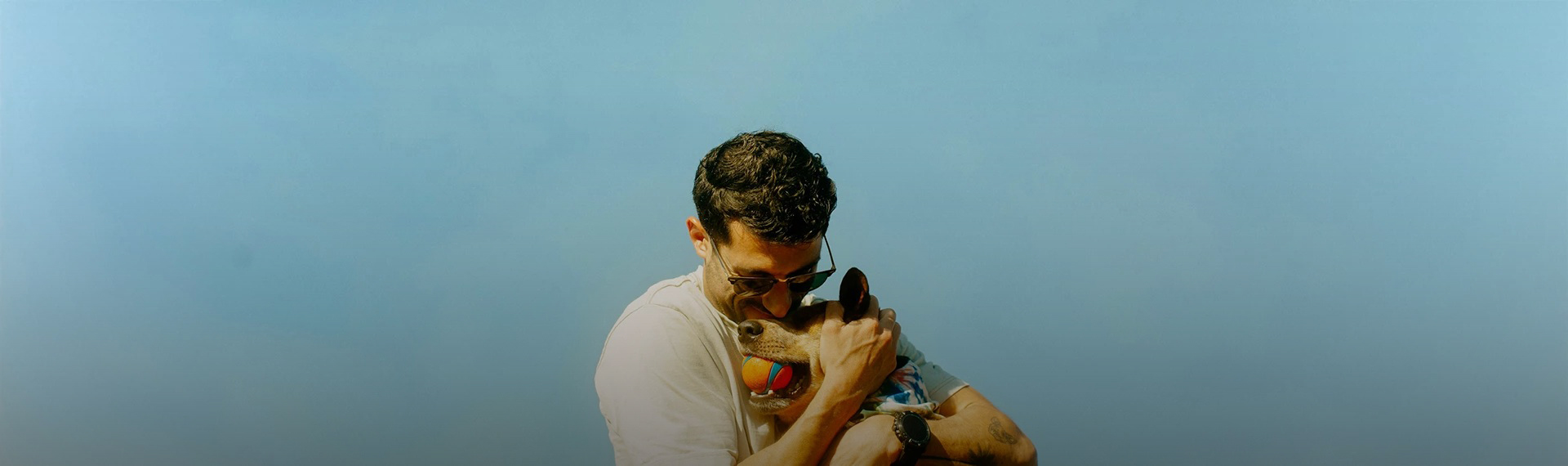 a man holding a dog with a ball in his mouth