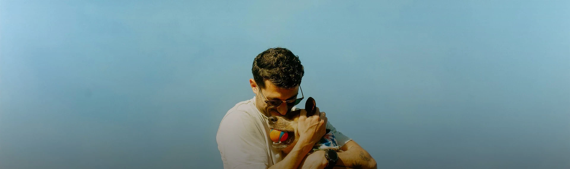 a man holding a dog with a ball in his mouth
