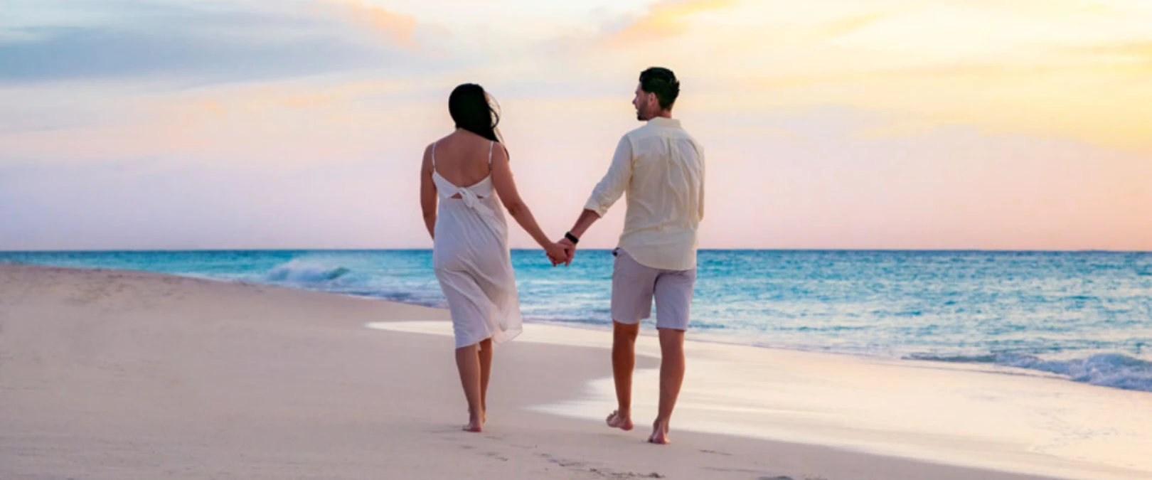 a man and woman holding hands on a beach