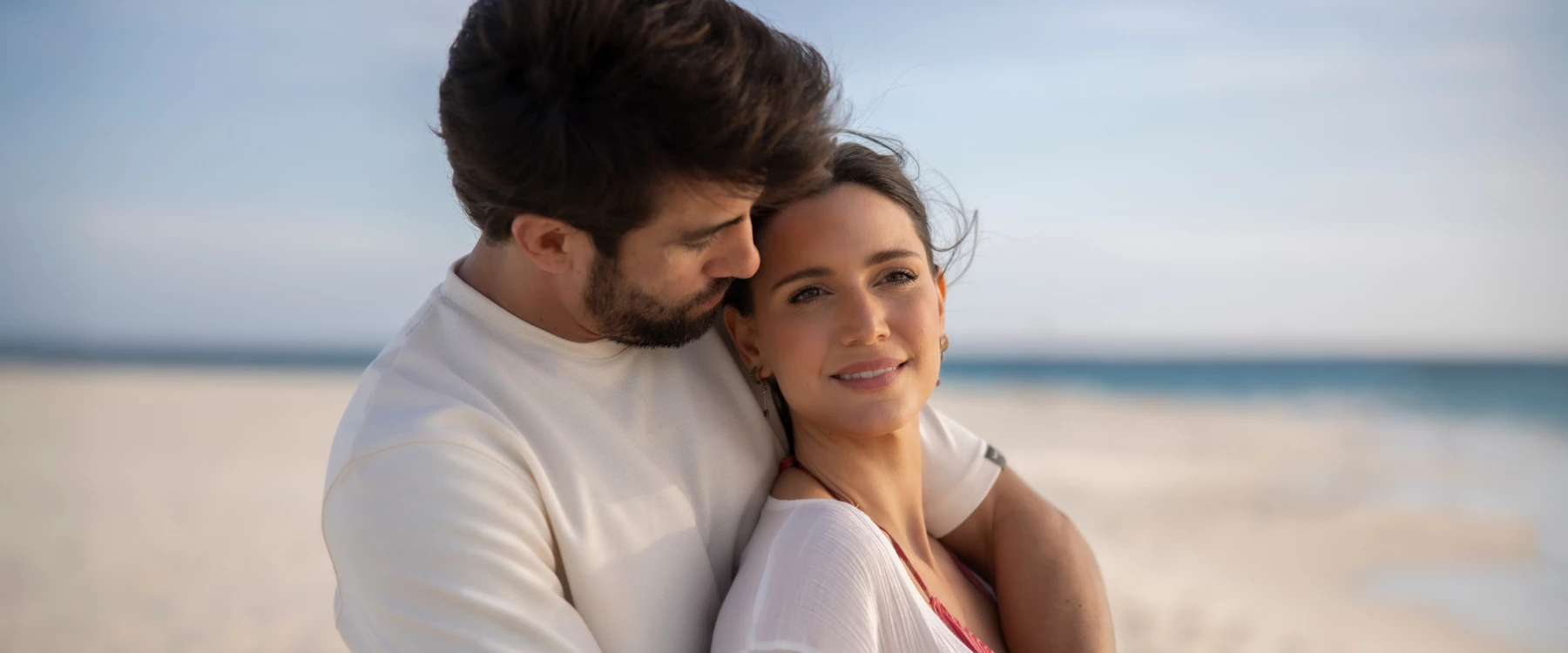 a man and woman standing together on a beach