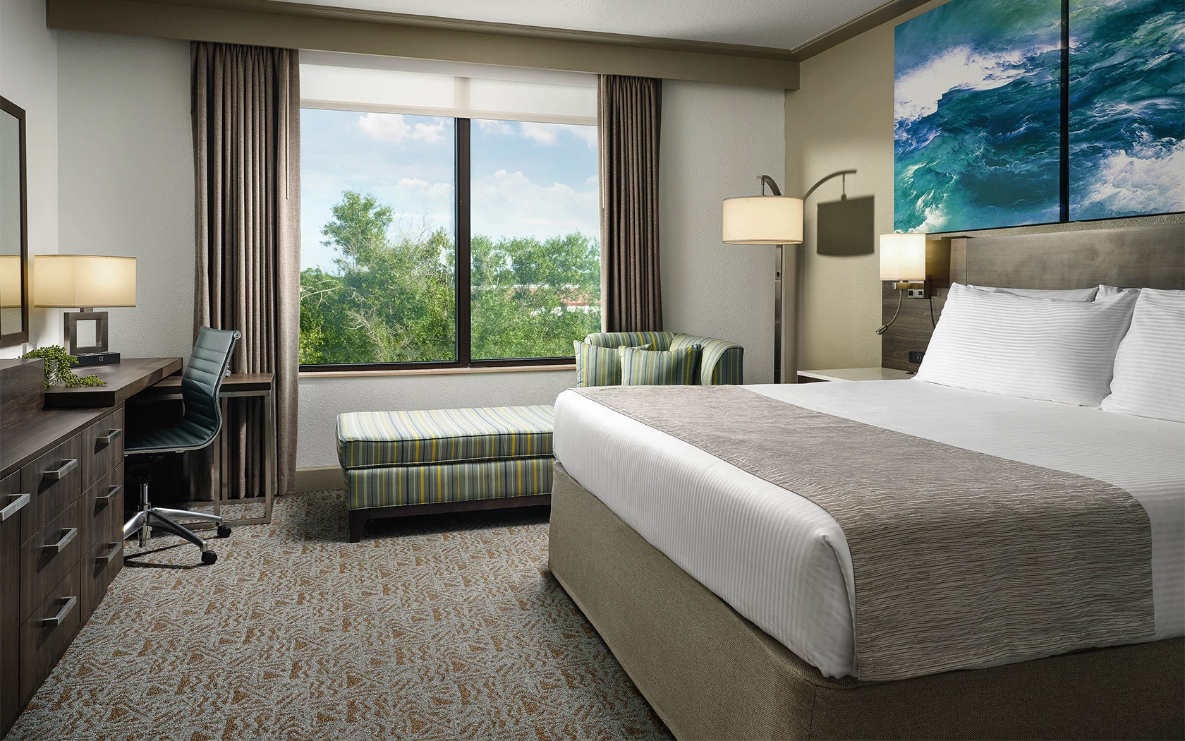 A hotel room with a large bed, desk, and window