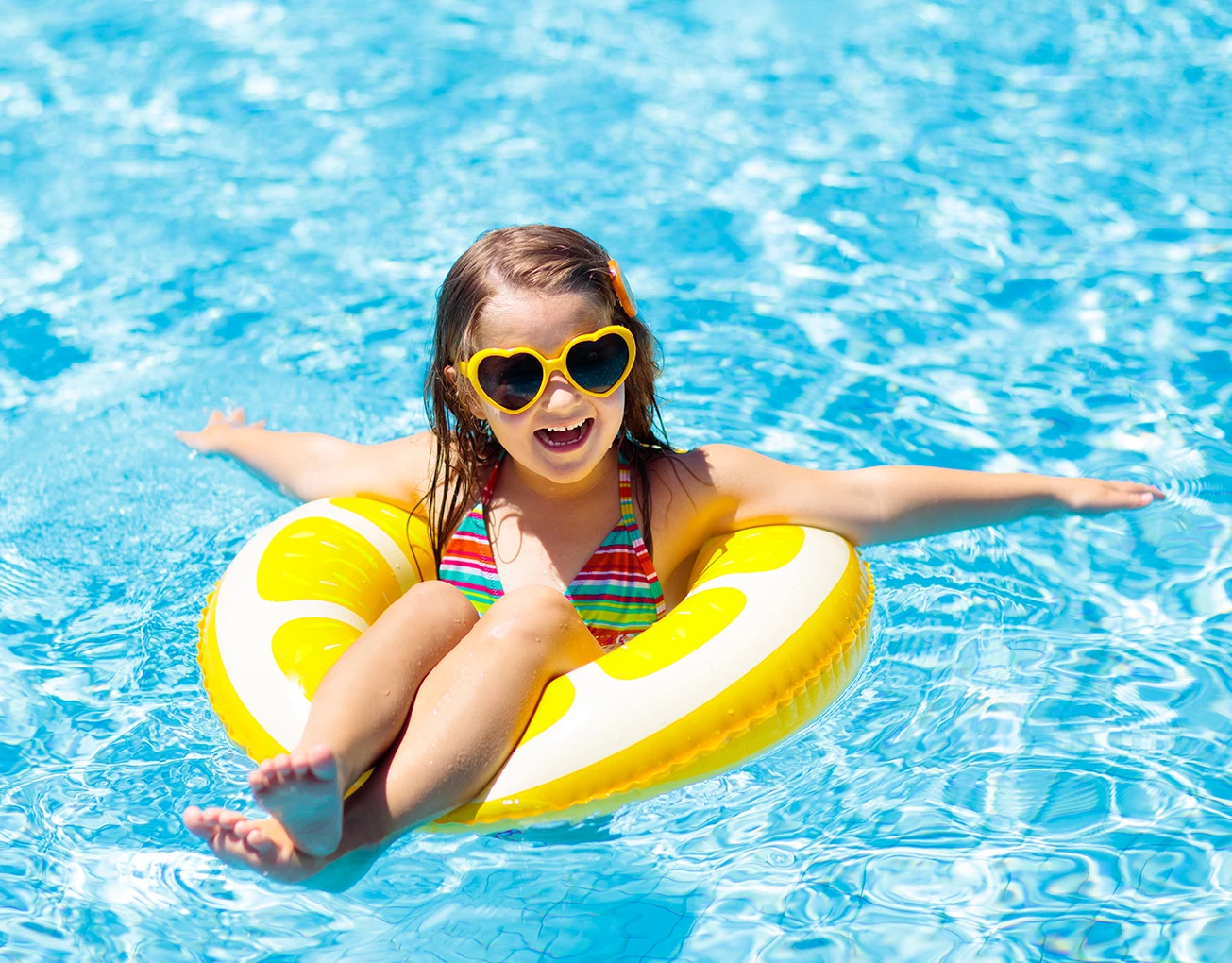 a girl in a pool wearing sunglasses and a swim ring