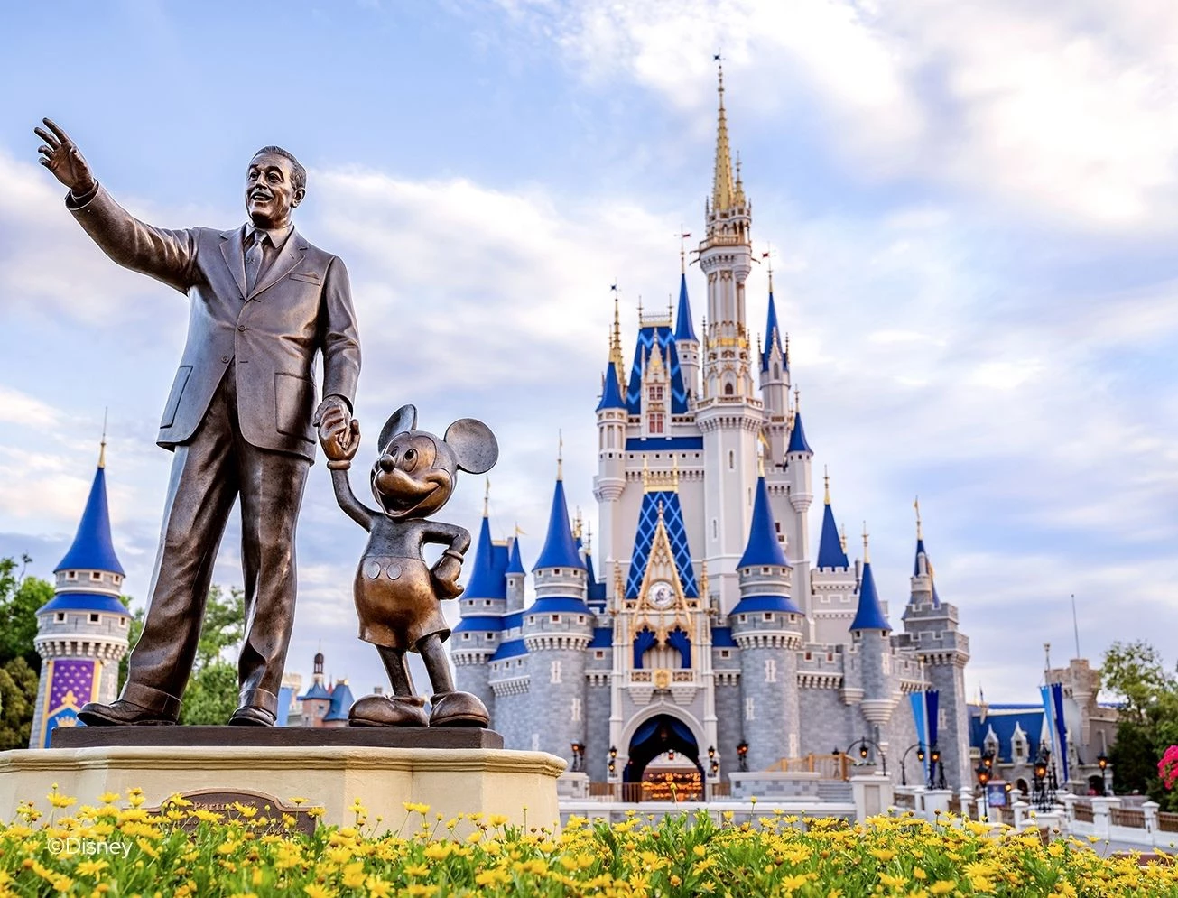 a statue of a man and mouse in front of a castle