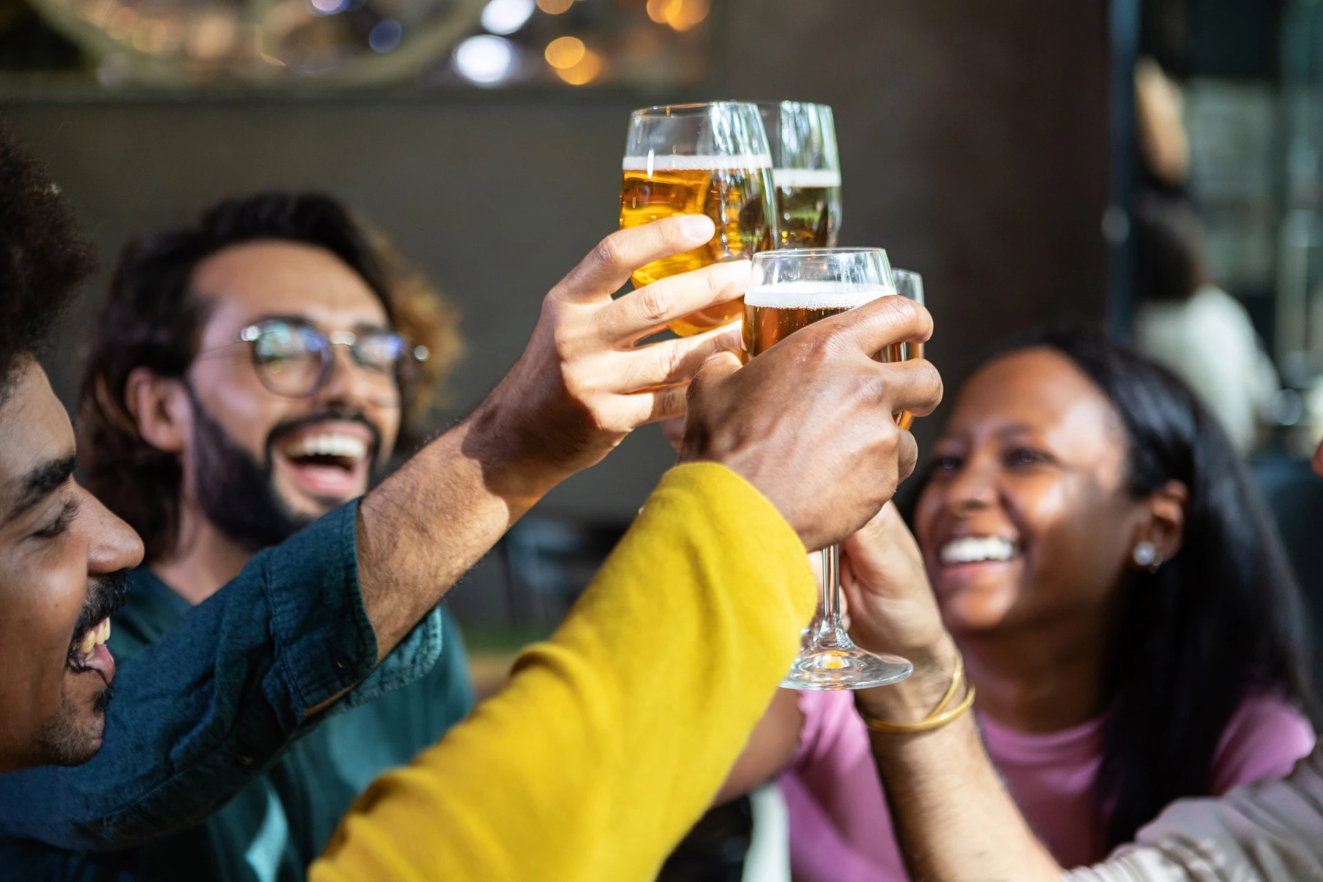 young group of multiracial people toasting beer and wine