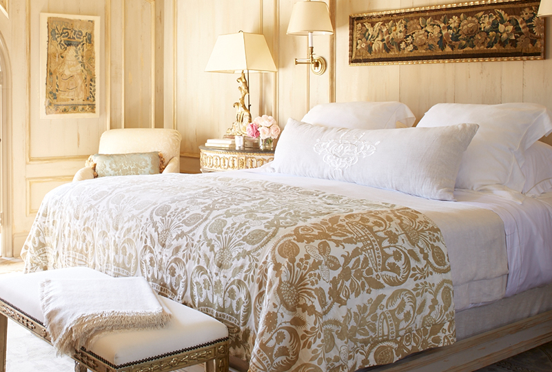a bed with a white blanket and a bench in a room