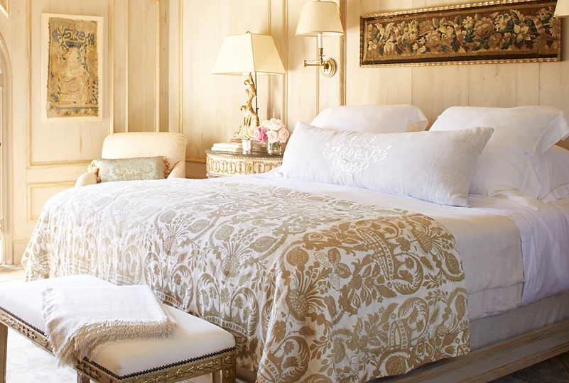 a bed with a white blanket and a bench in a room