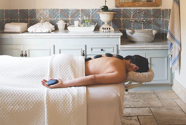 a person lying on a massage table with rocks on their back