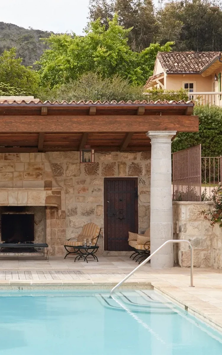 a pool with a stone building and a fireplace