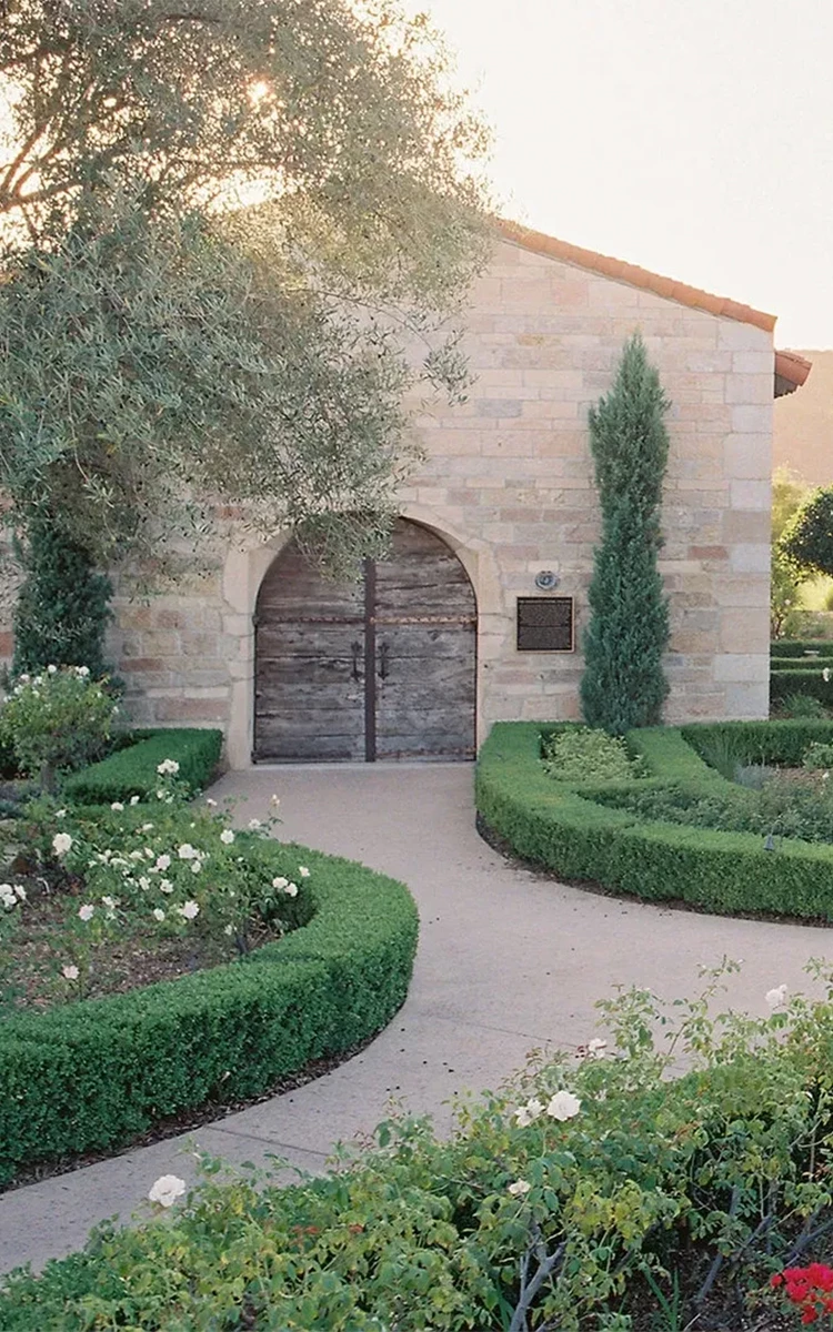 a stone building with a door and a garden