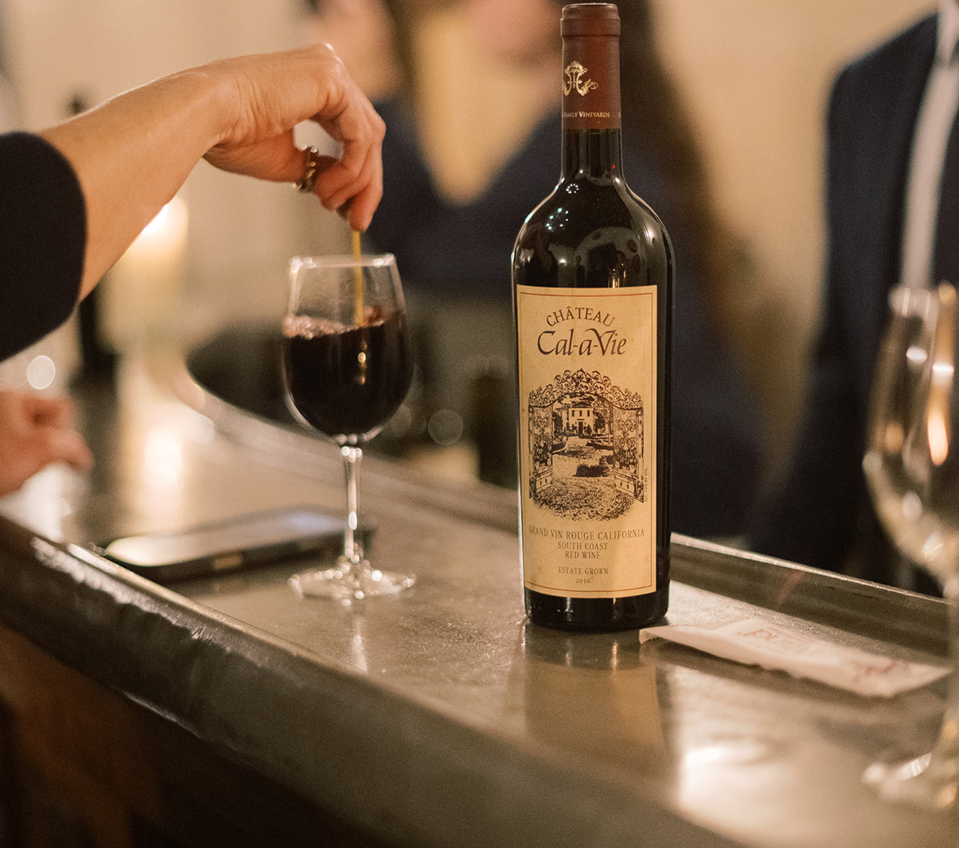 a person pouring a glass of wine into a glass