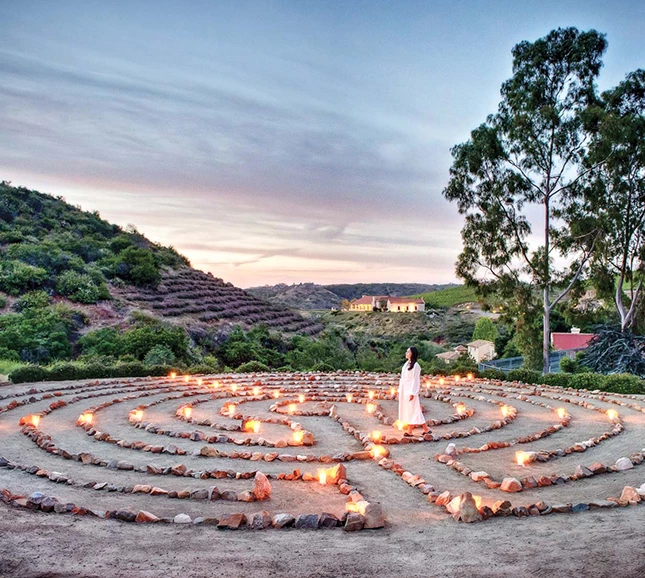 a woman standing in a labyrinth with lit candles