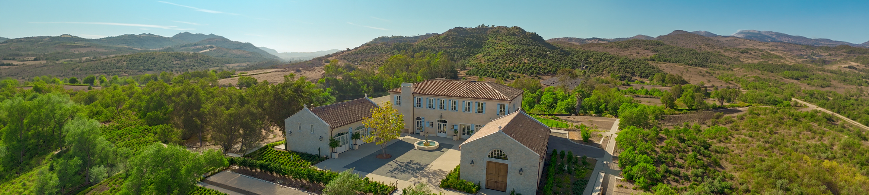 a large house with trees and a hill in the background