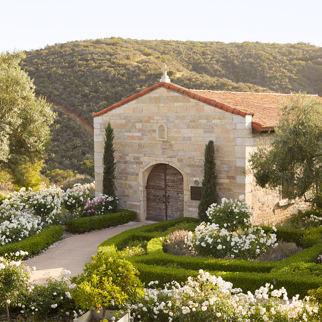 a stone building with a garden and bushes