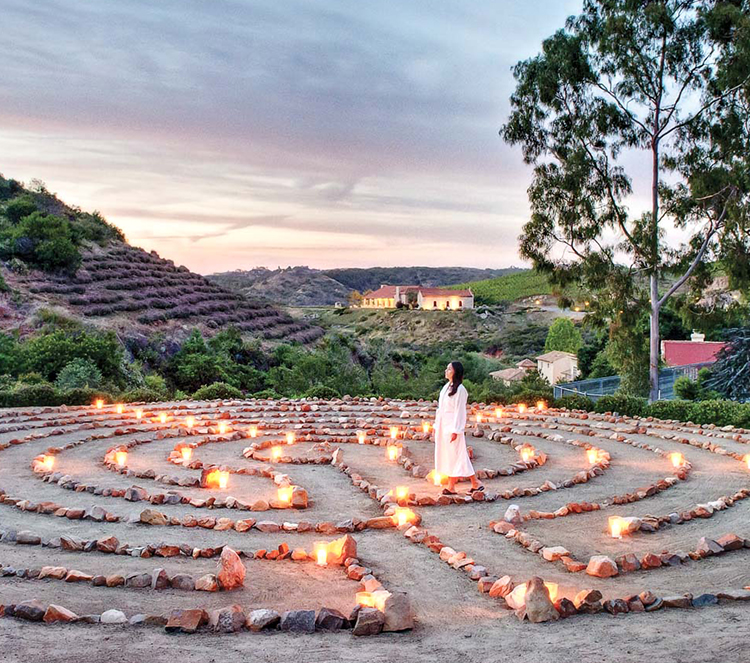 a woman standing in a labyrinth with candles