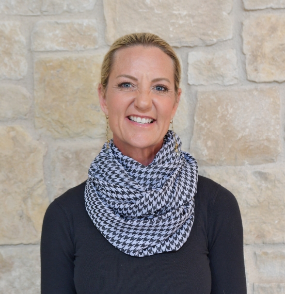 a woman smiling in front of a stone wall