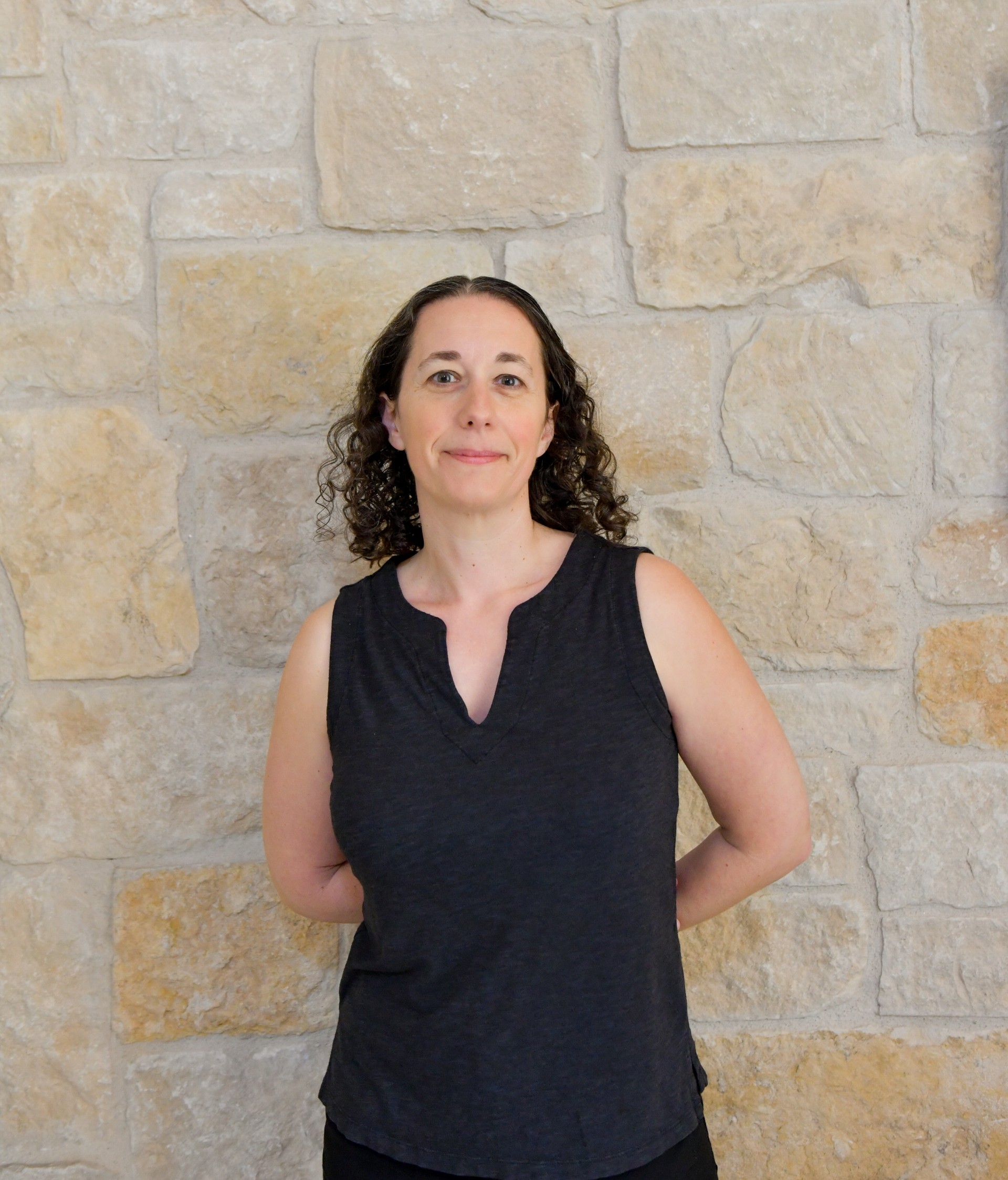 a woman standing in front of a stone wall