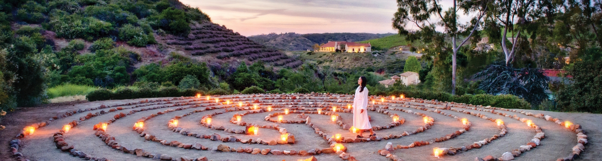 a woman standing in a labyrinth with candles