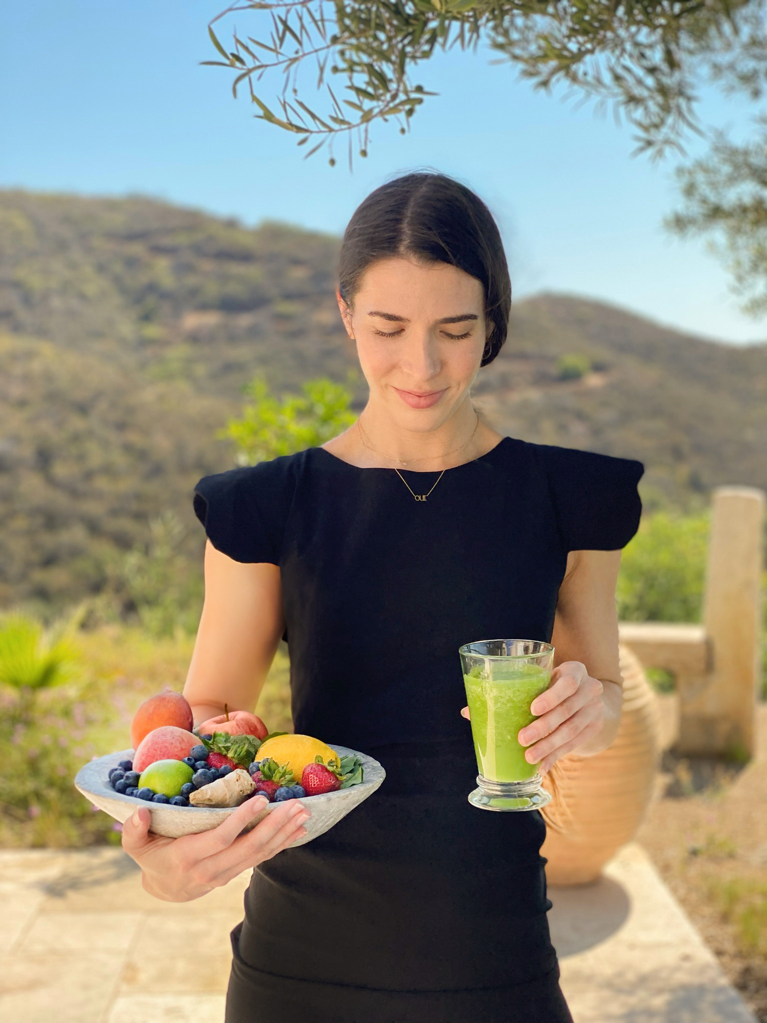 a woman holding a bowl of fruit and a glass of juice