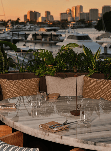 a table with chairs and a view of boats and water