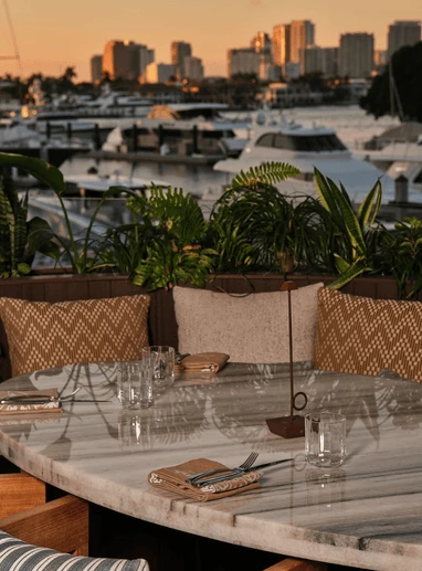 a table with chairs and a view of boats and water