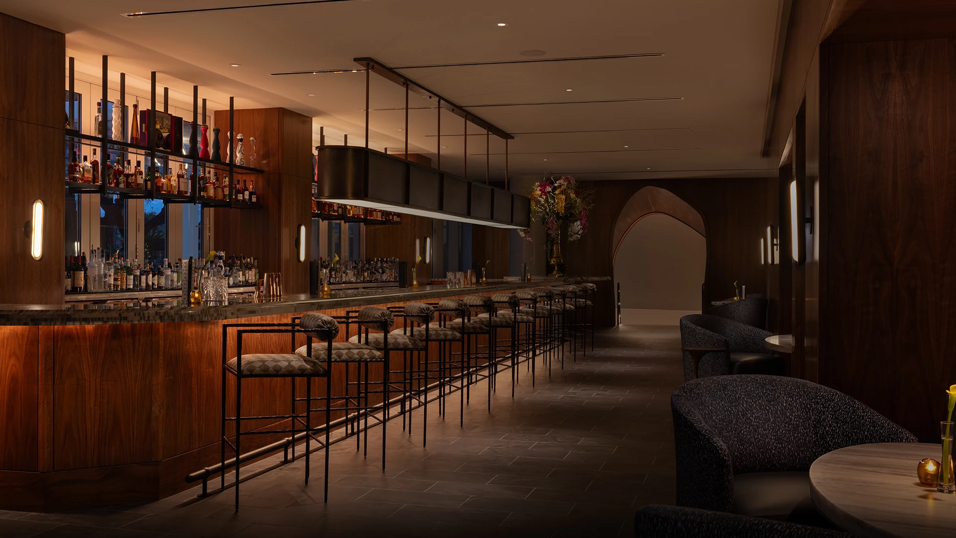 a bar with chairs and a shelf with bottles