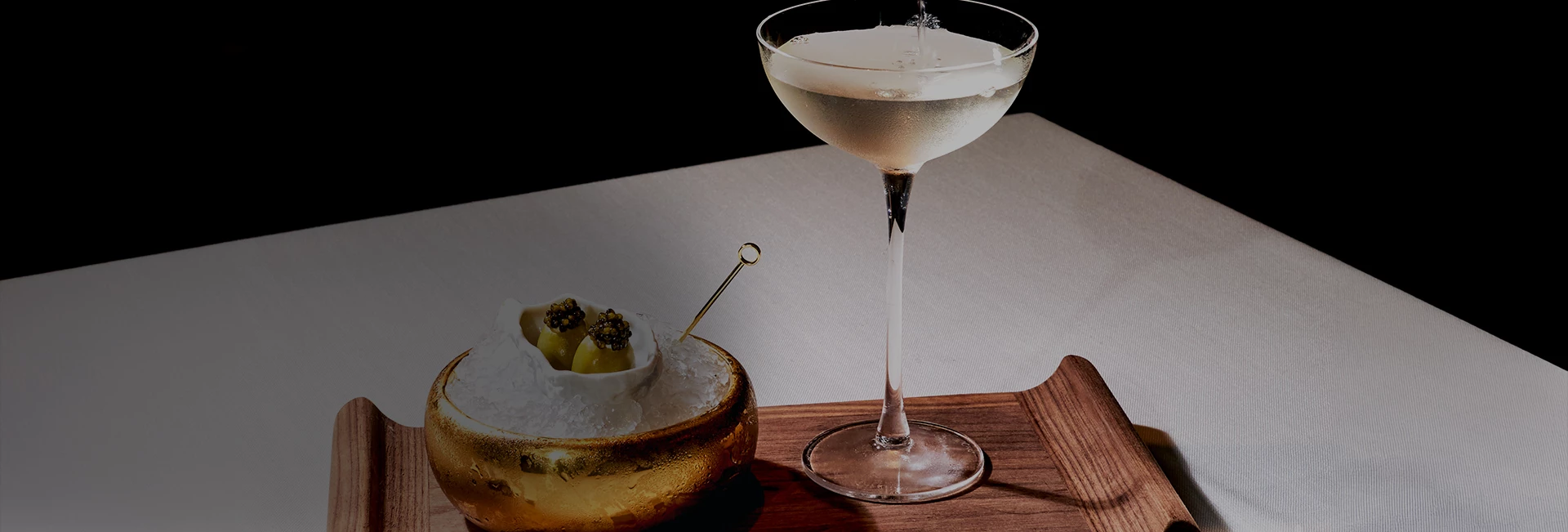 a glass of liquid next to a bowl of ice and a spoon