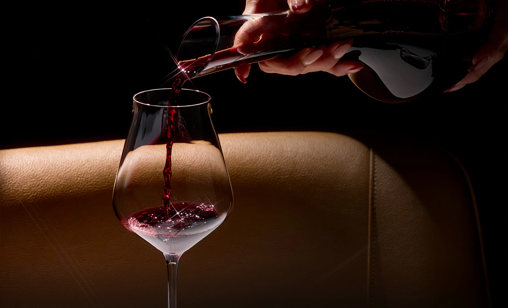 a person pouring red wine into a glass