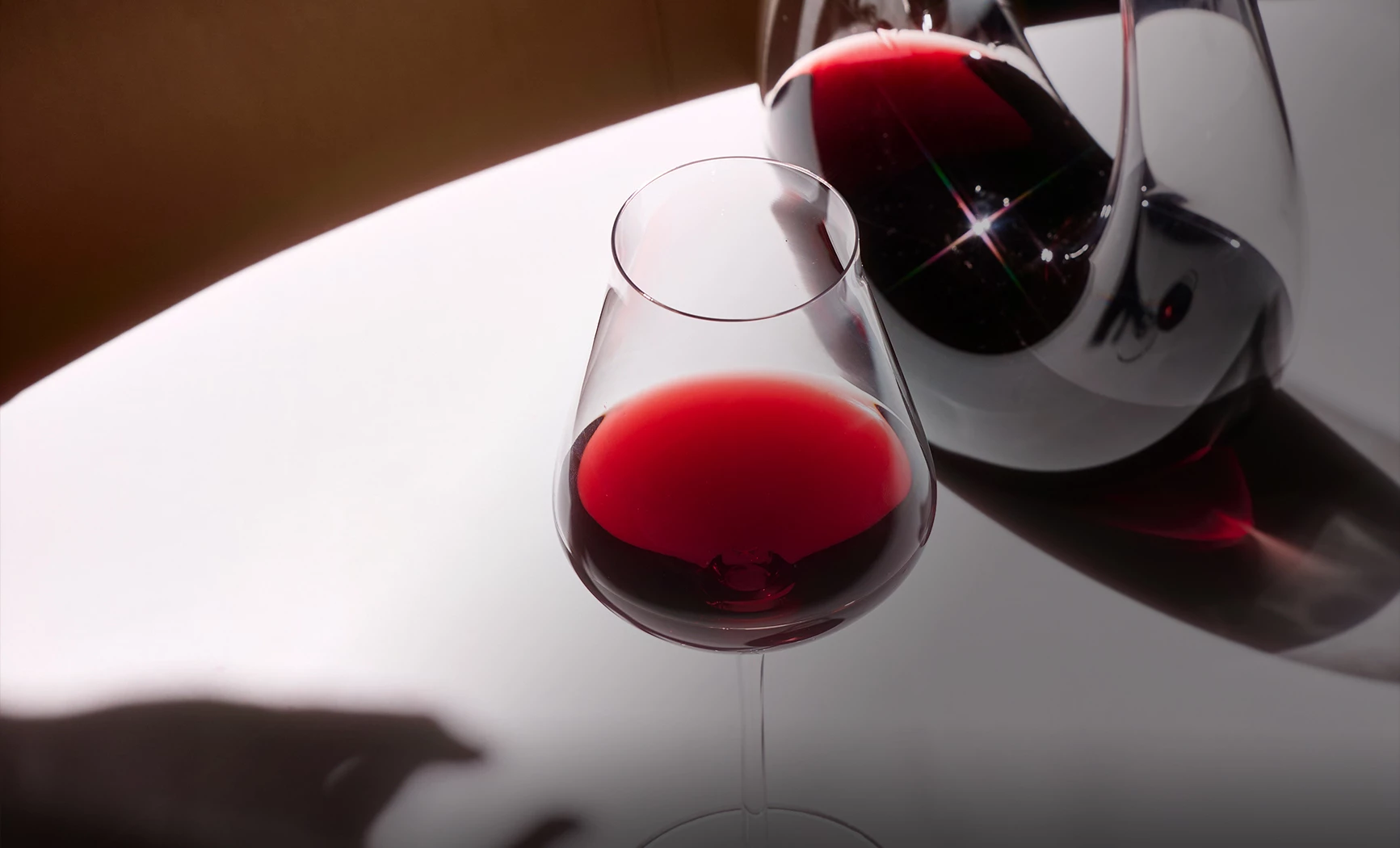 a glass of red wine next to a pitcher