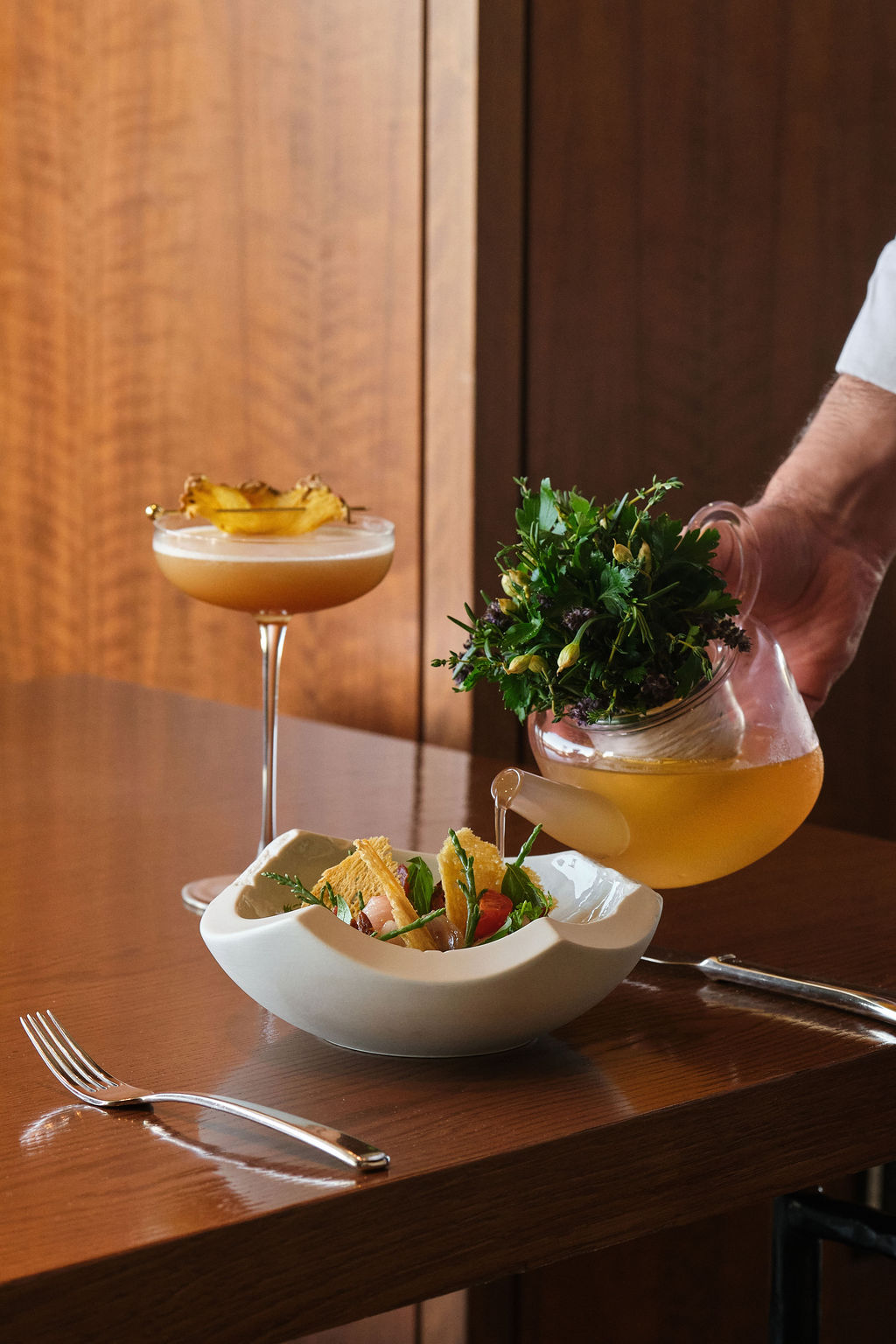 a person pouring liquid into a bowl of food