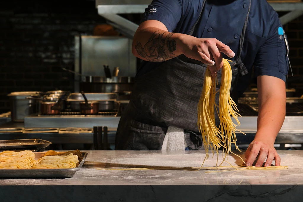 a person holding pasta in a kitchen