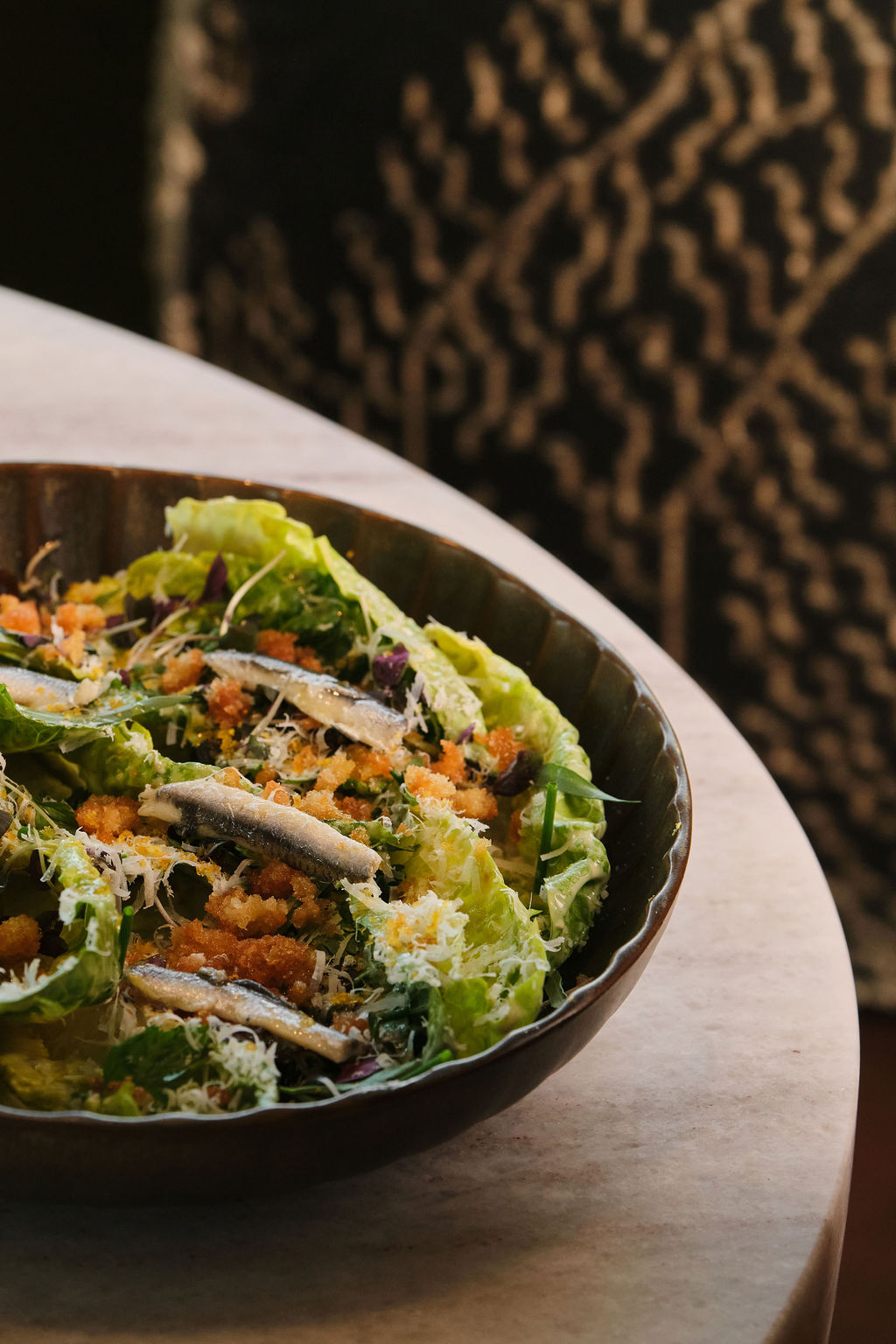 a bowl of salad with anchovies and parmesan cheese