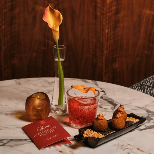 a table with a drink and a flower on it