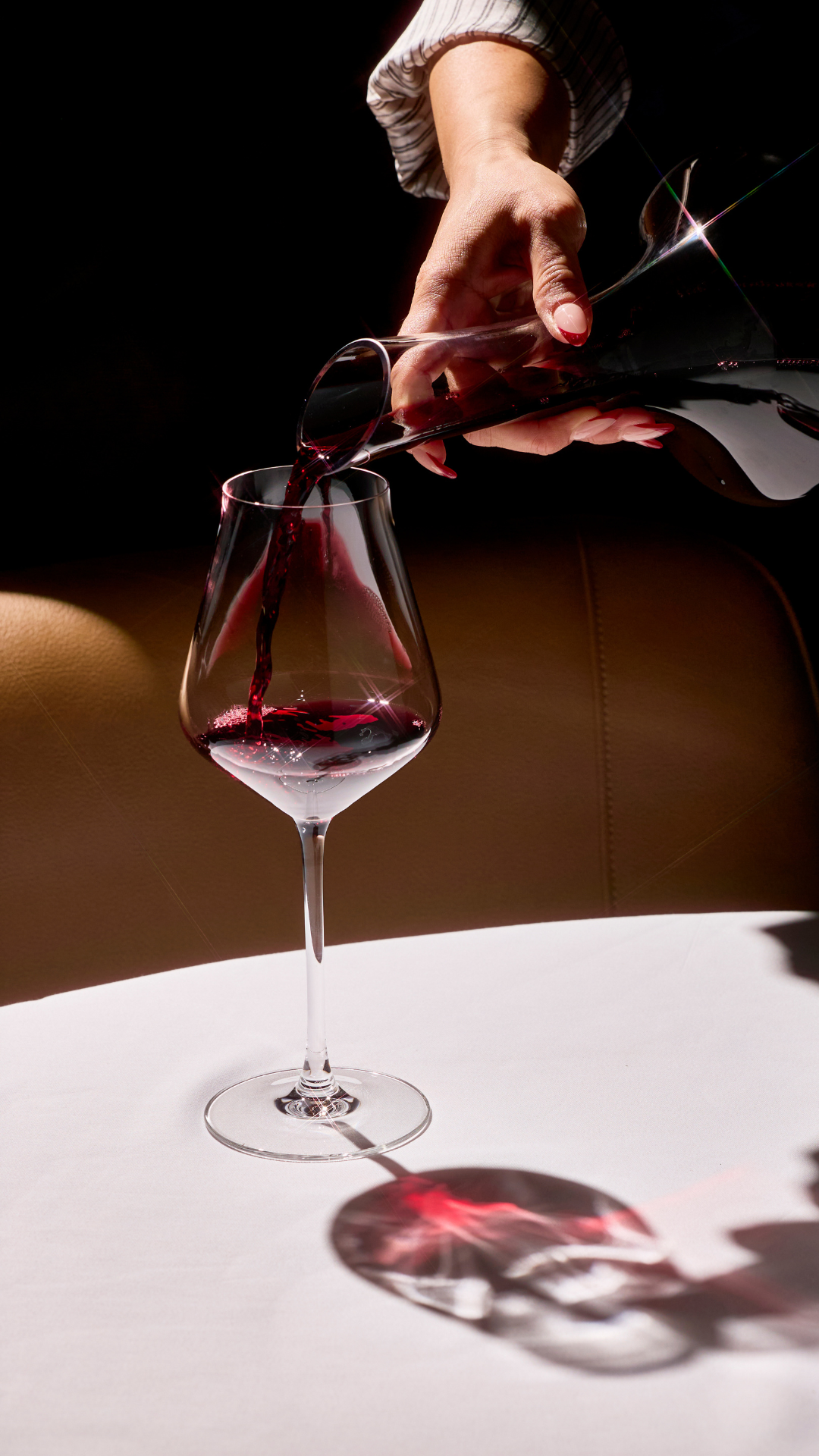 a hand pouring red wine into a glass