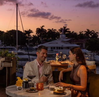 a man and woman sitting at a table with drinks