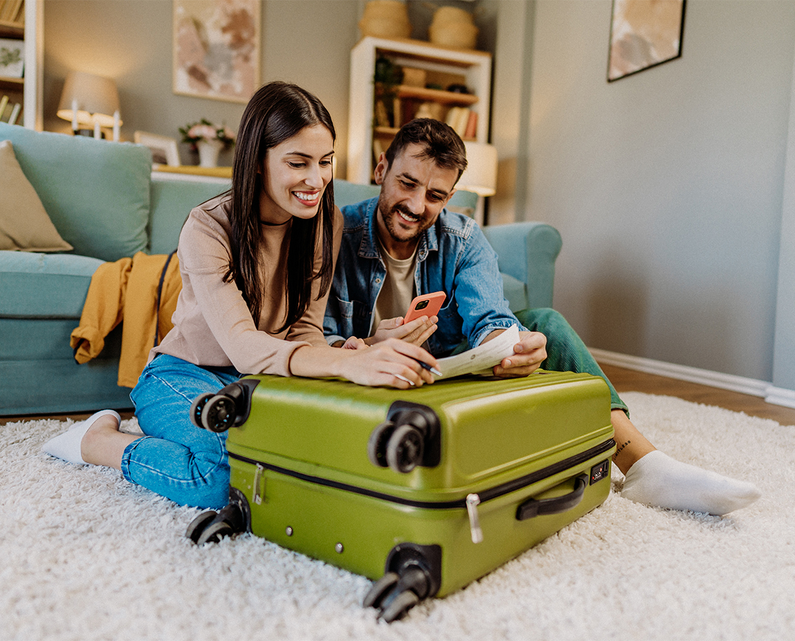 a man and woman sitting on the floor with a suitcase