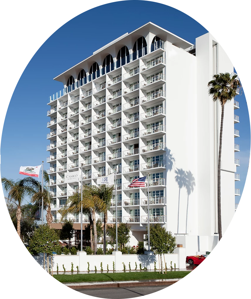 a white building with palm trees and flags