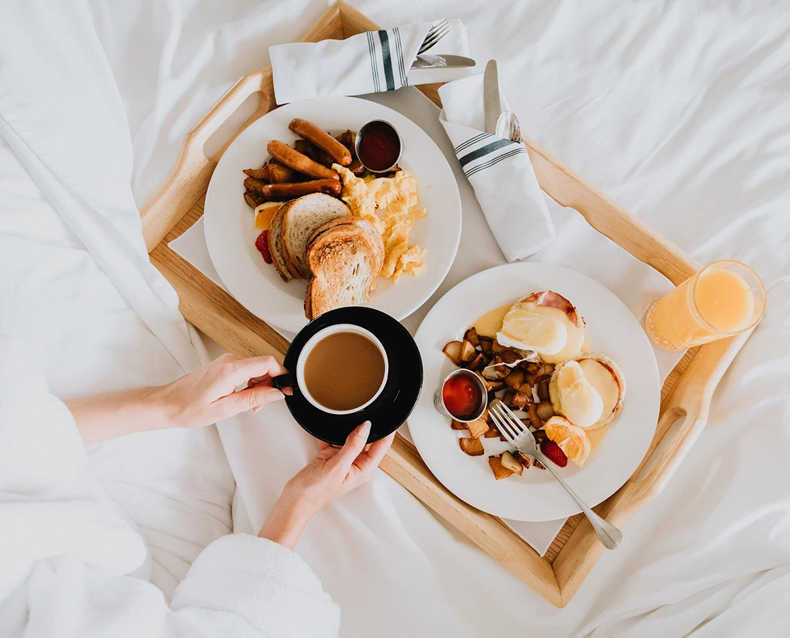 a person holding a cup of coffee and a plate of food