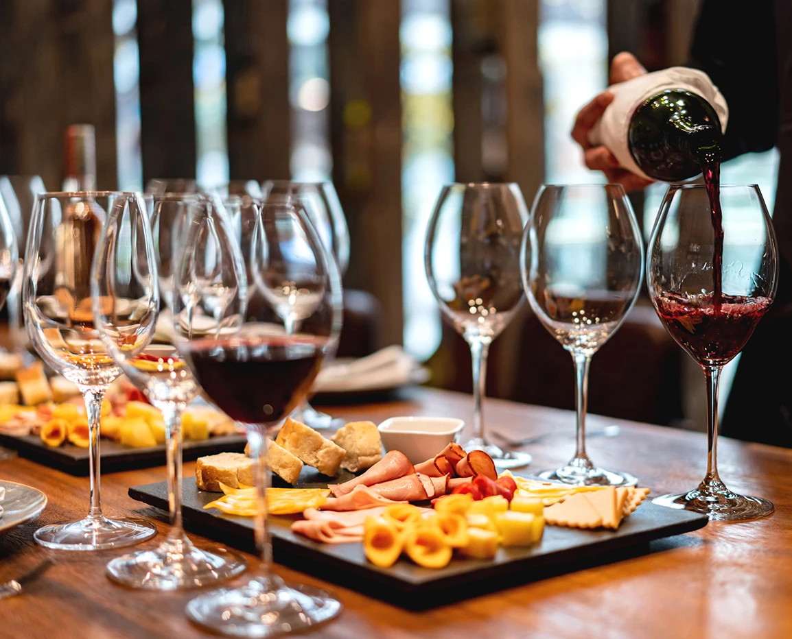 a person pouring wine into wine glasses
