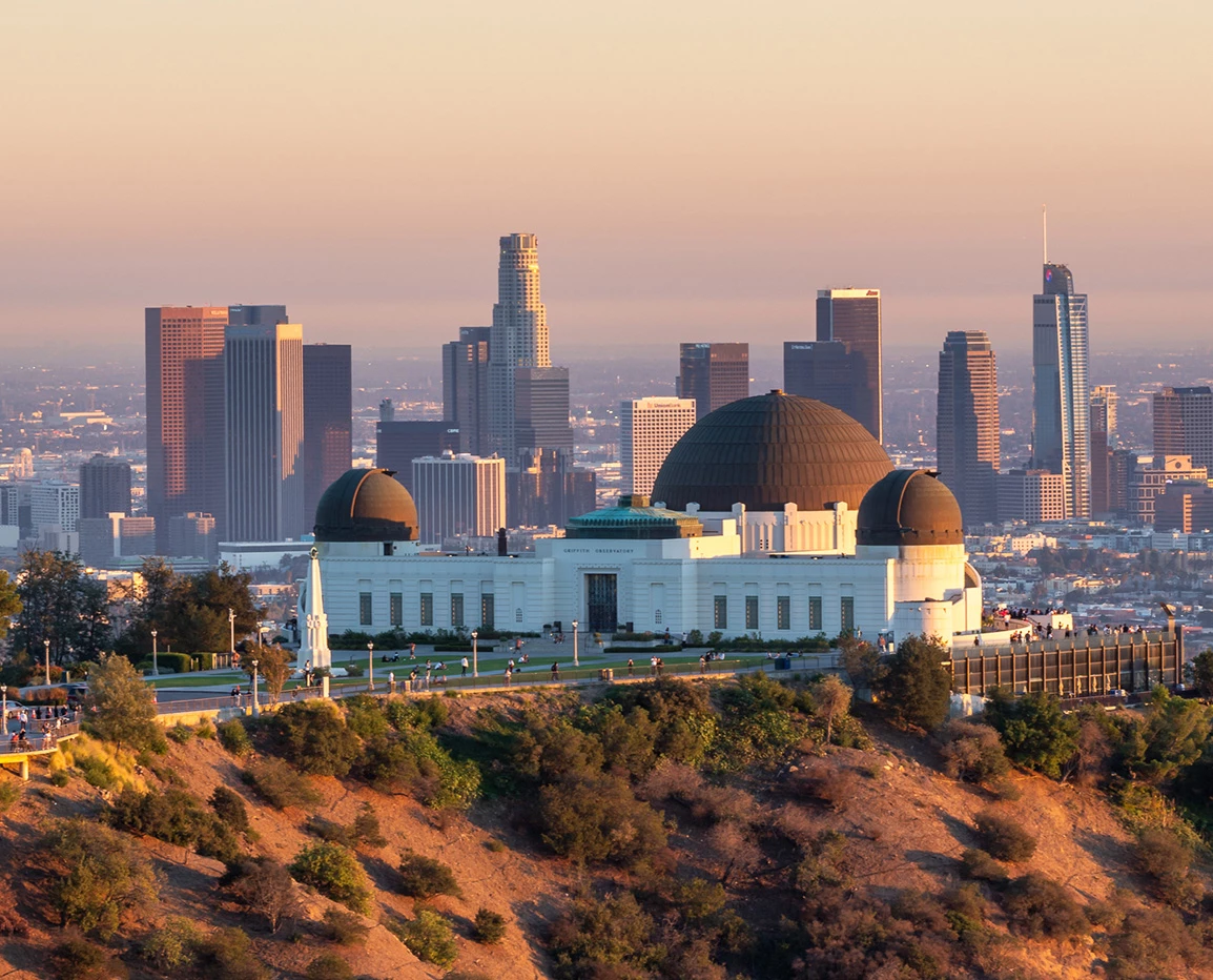 a large white building with black domes on a hill with a city in the background