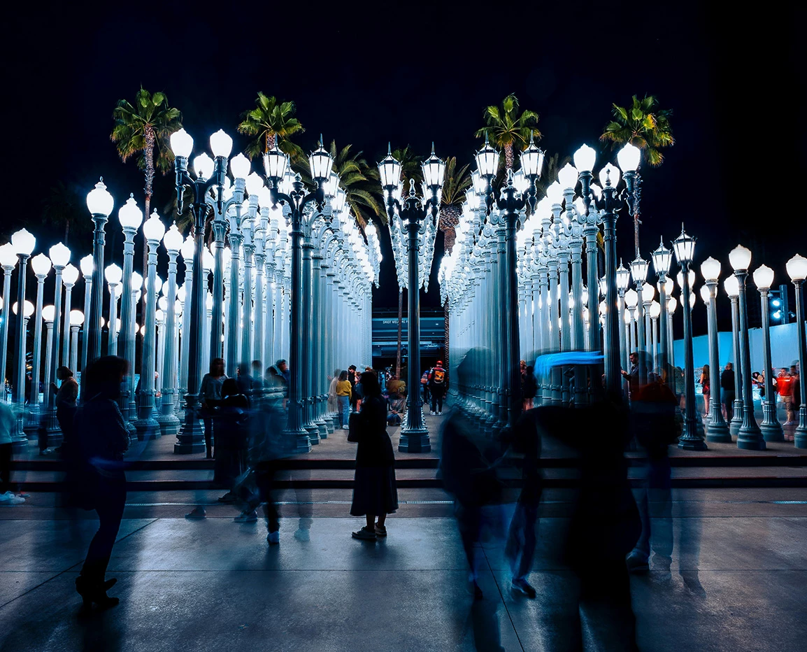 a group of people walking on a walkway with street lights