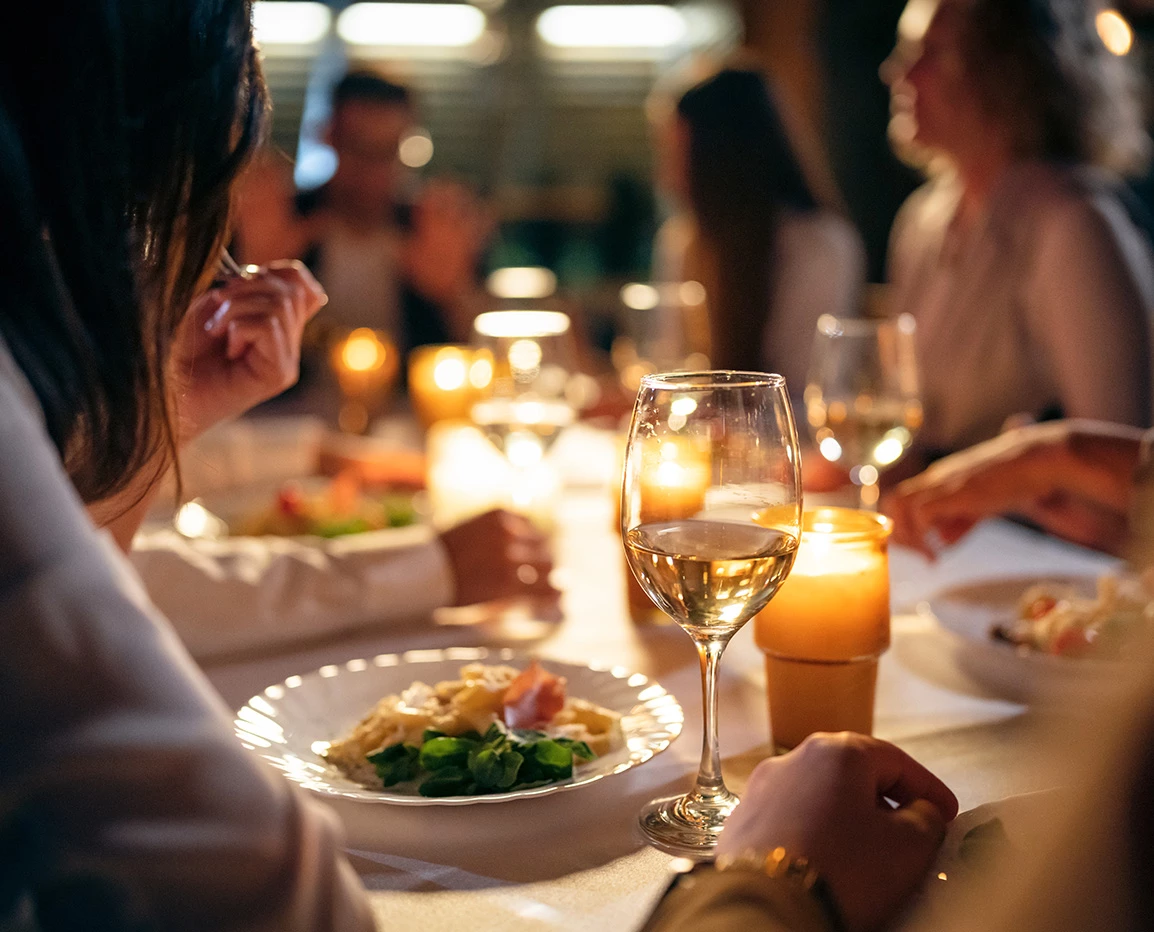 a group of people sitting at a table with food and wine glasses