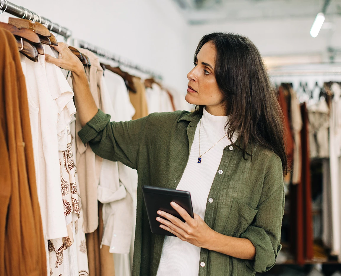 a woman holding a tablet and looking at clothes
