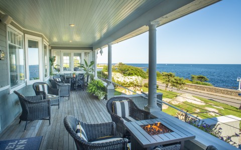 a deck with chairs and a fire pit overlooking the ocean
