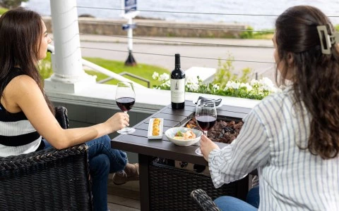 a woman holding a glass of wine and a plate of food on a table