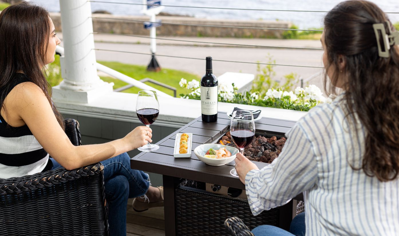 a couple of people sitting at a table with food and wine