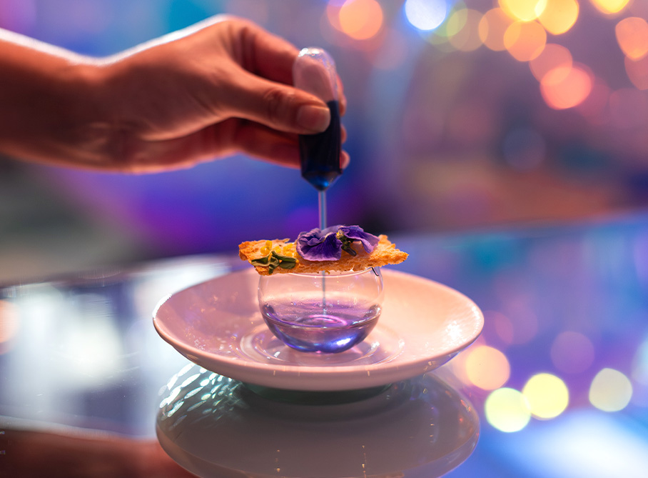 a person pouring liquid into a glass bowl