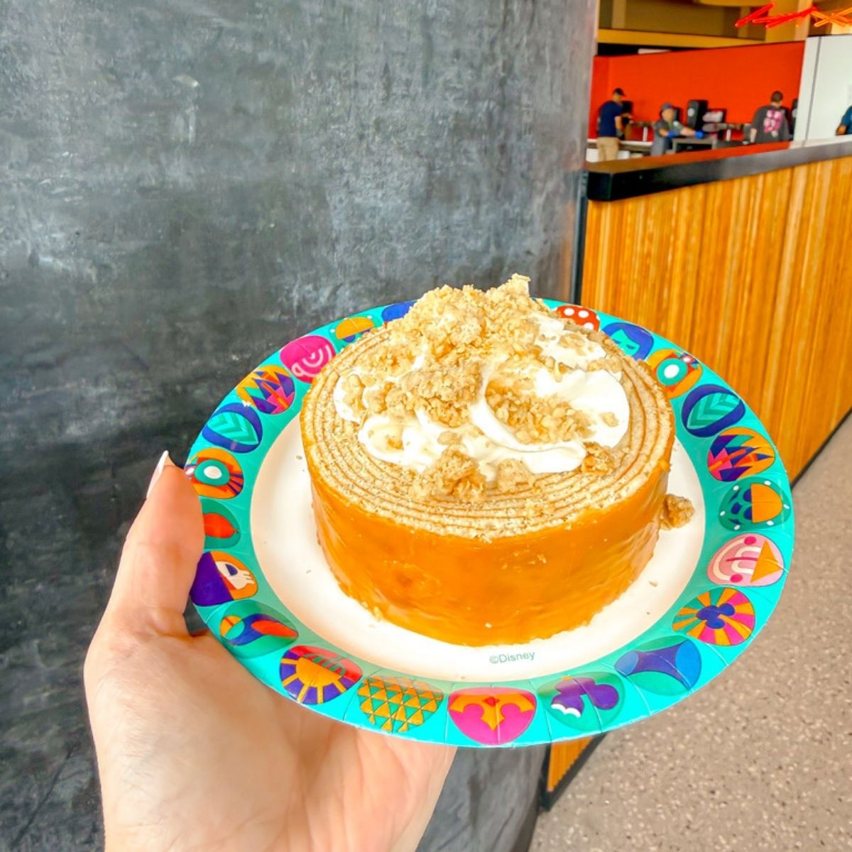 a hand holding a plate of cake