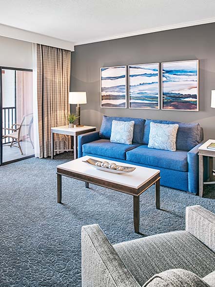 living room area with blue couch coffee table and view of the balcony